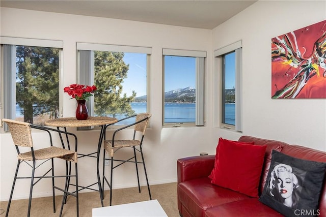 carpeted dining space featuring a water view and baseboards