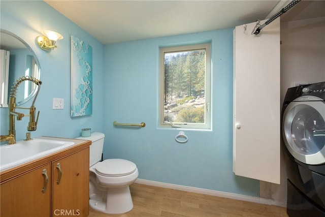 bathroom featuring vanity, wood finished floors, washer / dryer, and baseboards