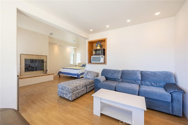 living area featuring a high end fireplace, recessed lighting, and light wood-style floors