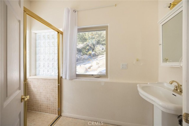 bathroom with baseboards, a stall shower, tile patterned flooring, and a sink