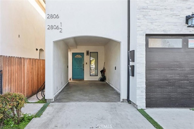 view of exterior entry with fence and stucco siding