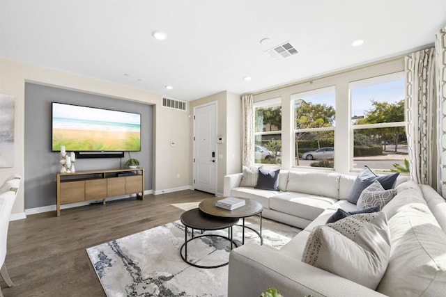 living room with recessed lighting, visible vents, baseboards, and wood finished floors