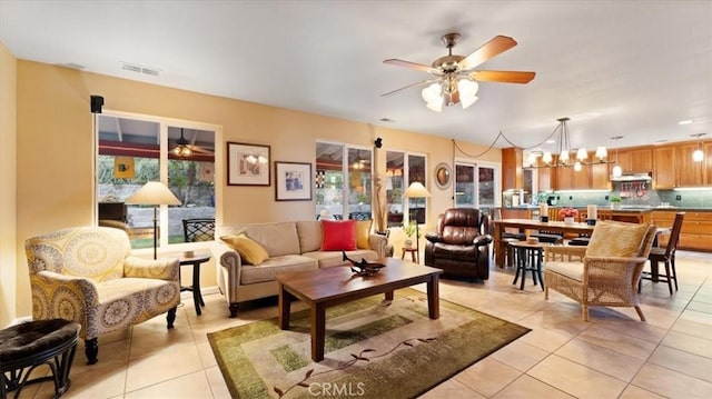 tiled living room featuring ceiling fan with notable chandelier