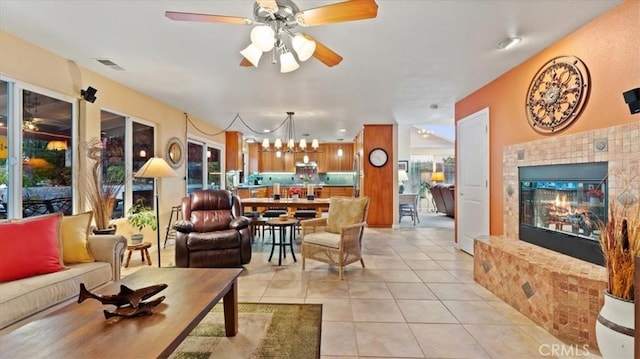 tiled living room featuring ceiling fan with notable chandelier and a tile fireplace