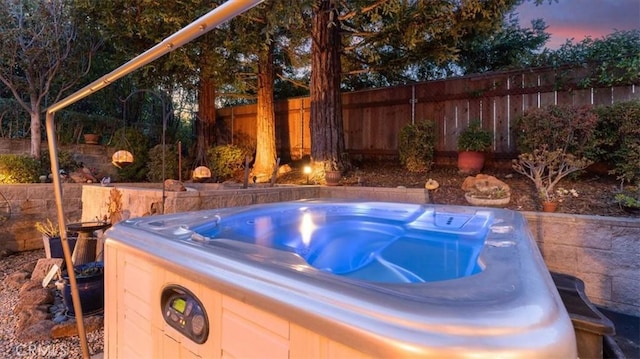 pool at dusk featuring a hot tub