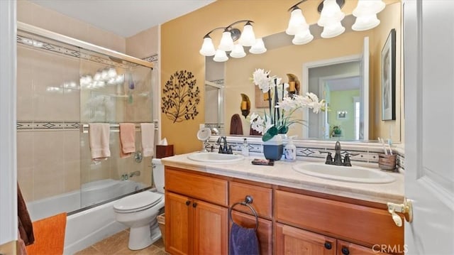 full bathroom with toilet, vanity, bath / shower combo with glass door, and tile patterned flooring