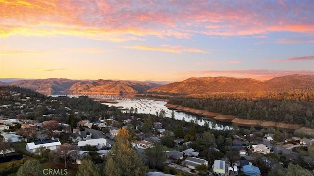 aerial view at dusk featuring a water and mountain view