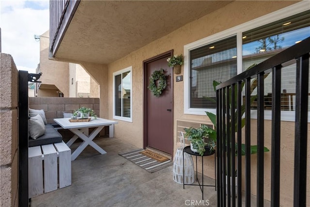 entrance to property featuring fence, a patio, and stucco siding