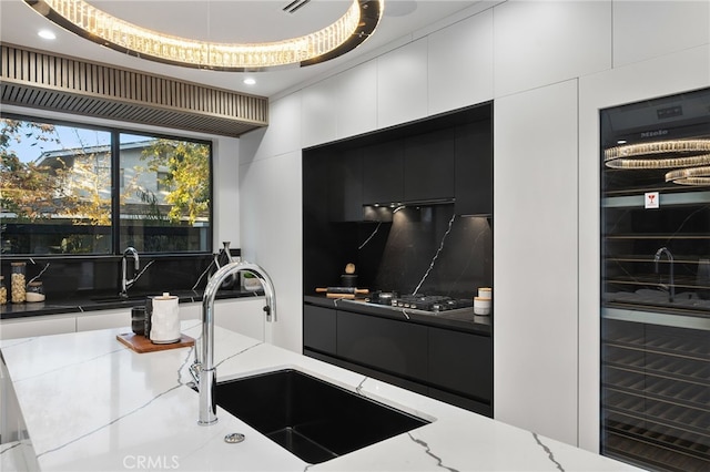 interior space with stainless steel gas cooktop, sink, tasteful backsplash, dark stone countertops, and a raised ceiling