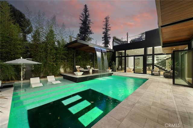 pool at dusk featuring a patio