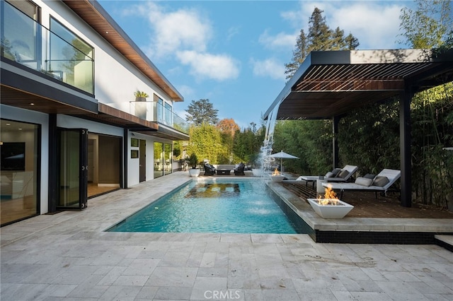 view of swimming pool featuring pool water feature, an outdoor fire pit, and a patio