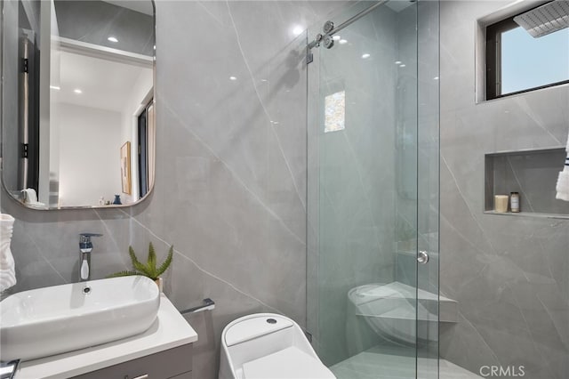 bathroom with tile walls, an enclosed shower, vanity, and toilet