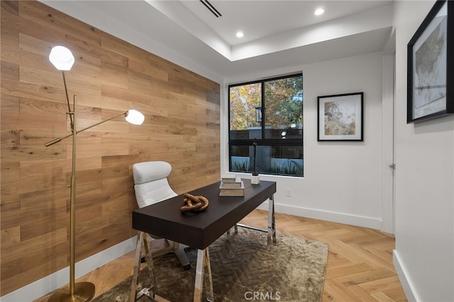 office space featuring a tray ceiling, parquet floors, and wood walls