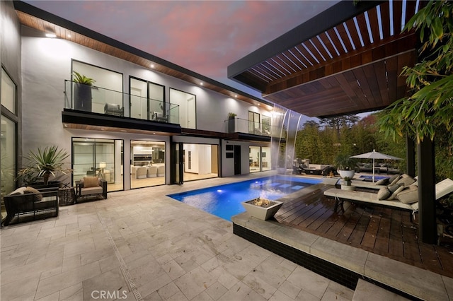 pool at dusk featuring a pergola and a patio area