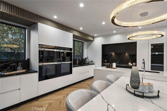 kitchen with dark stone countertops, double wall oven, light parquet flooring, decorative backsplash, and white cabinets