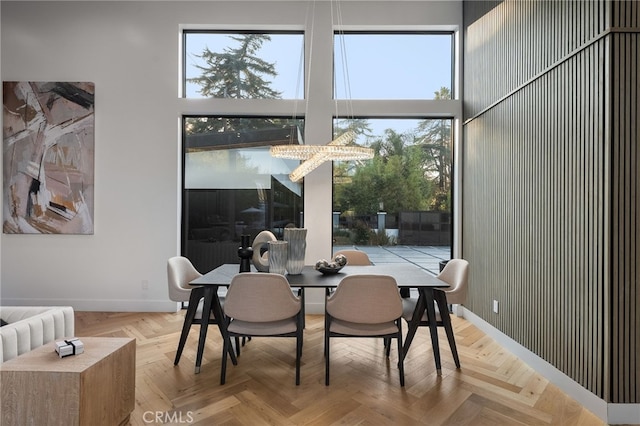 dining space featuring a towering ceiling and light parquet flooring