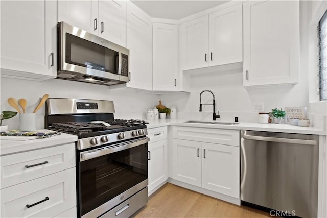 kitchen featuring white cabinetry, appliances with stainless steel finishes, sink, and light wood-type flooring