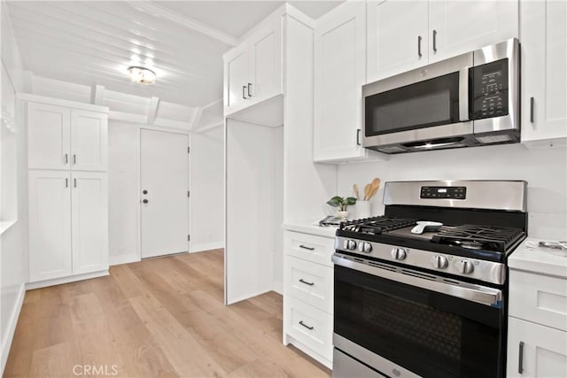 kitchen featuring white cabinetry, crown molding, light wood-type flooring, and appliances with stainless steel finishes