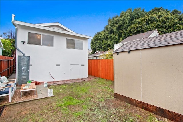 rear view of house featuring a patio, an outdoor structure, and a yard