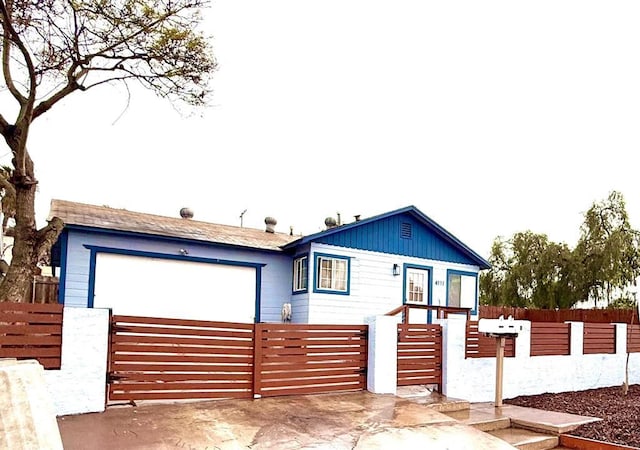 ranch-style home featuring a garage, driveway, and a fenced front yard