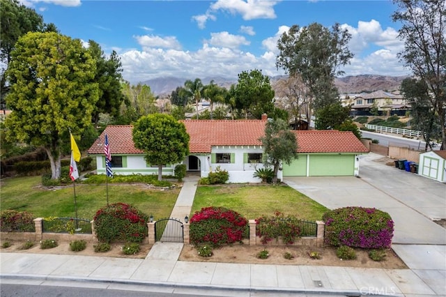 mediterranean / spanish house featuring a fenced front yard, a gate, a tile roof, and driveway