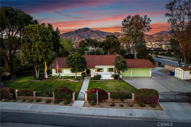 mediterranean / spanish-style home with a fenced front yard, a gate, a mountain view, and a tiled roof