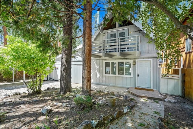 back of house featuring board and batten siding, fence, and a balcony