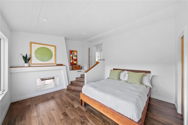 bedroom featuring baseboards and dark wood-style flooring