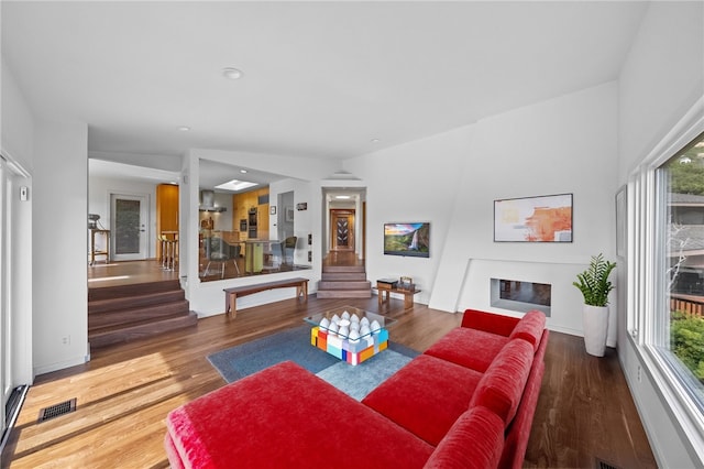 living area featuring stairs, visible vents, a fireplace, and wood finished floors