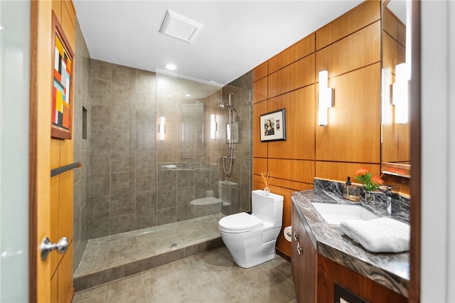 bathroom featuring a walk in shower, toilet, wooden walls, vanity, and tile patterned floors