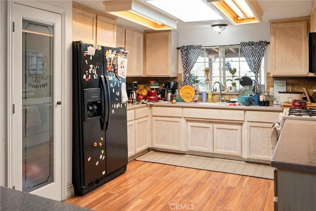 kitchen featuring backsplash, light hardwood / wood-style floors, black refrigerator with ice dispenser, and light brown cabinets