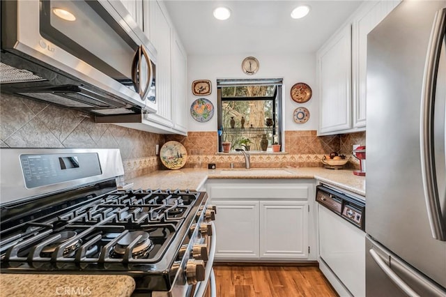 28010 Tiffany Ln Unit 309, Canyon Country, CA 91387 - kitchen with appliances with stainless steel finishes, a sink, white cabinets, light wood-style flooring, and recessed lighting