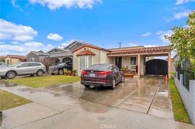 view of front facade with driveway, a tiled roof, a gate, fence, and stucco siding