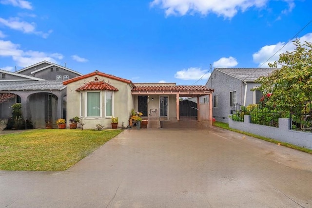 view of front of house with driveway, a tiled roof, fence, a front yard, and stucco siding