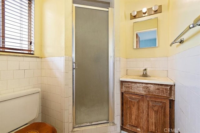 bathroom featuring vanity, a shower with door, and tile walls