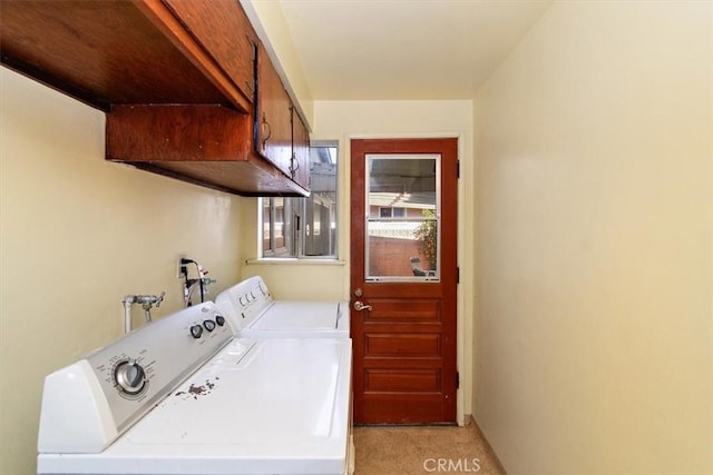 clothes washing area featuring cabinets and washer and clothes dryer