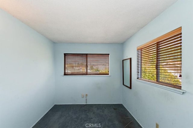 unfurnished room featuring dark carpet