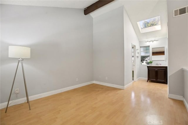 unfurnished room featuring light wood-type flooring and lofted ceiling with skylight