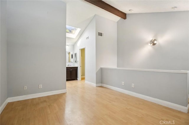 empty room with light hardwood / wood-style floors, high vaulted ceiling, beamed ceiling, and a skylight