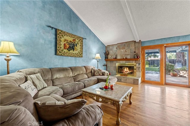 living room featuring vaulted ceiling with beams, a textured ceiling, a fireplace, and wood finished floors