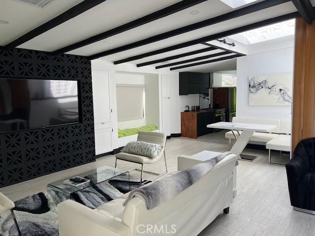 living room featuring light wood-type flooring and beam ceiling