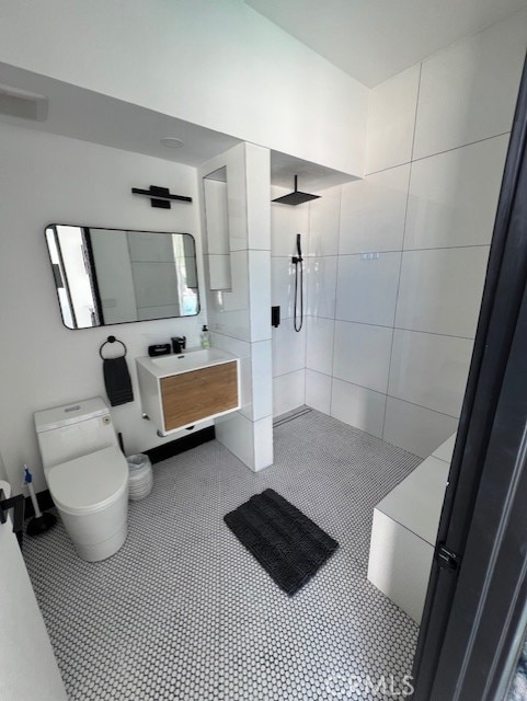 bathroom with tile patterned flooring, vanity, toilet, and tiled shower