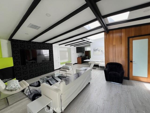 living room with light hardwood / wood-style flooring and beamed ceiling