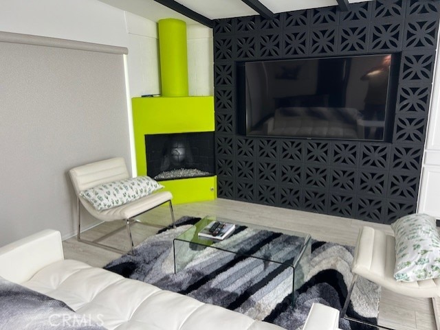 living area featuring beamed ceiling and wood-type flooring