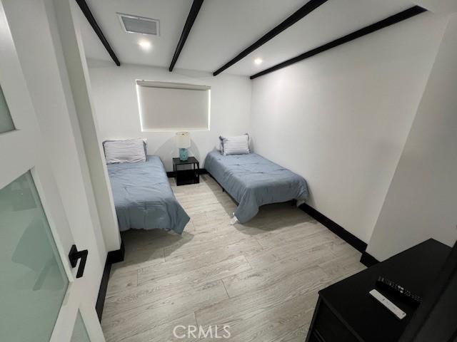 bedroom with beam ceiling and light wood-type flooring