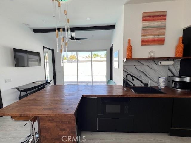 kitchen with beam ceiling, black microwave, and ceiling fan