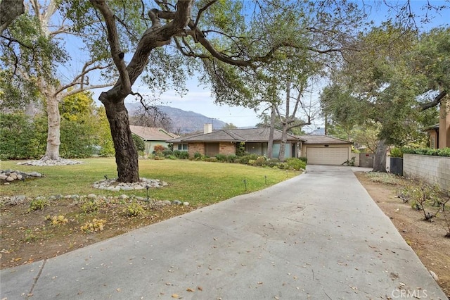 ranch-style house featuring a mountain view, a front lawn, and a garage