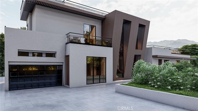 rear view of property featuring a balcony, a garage, and a mountain view