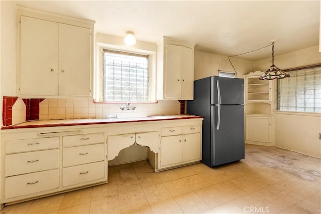 kitchen with sink, pendant lighting, stainless steel refrigerator, and backsplash