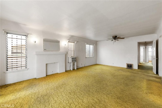 unfurnished living room with a fireplace, heating unit, carpet flooring, and ceiling fan